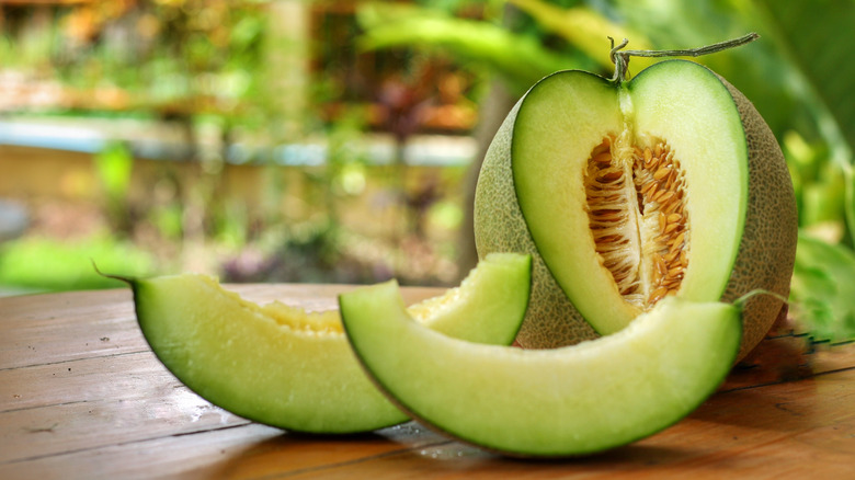 A partially cut up honeydew melon next to it's two removed slices 