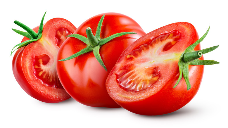 A whole tomato between halves of a tomato 