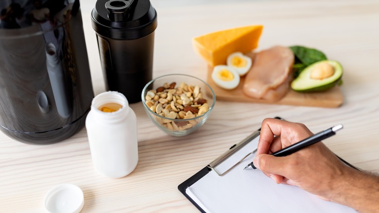 person taking notes near healthy foods