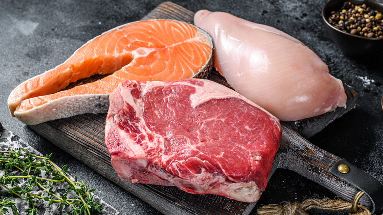 Raw salmon, chicken, and beef on cutting board