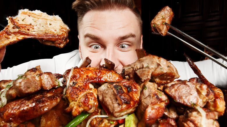 man eating assorted grilled meats