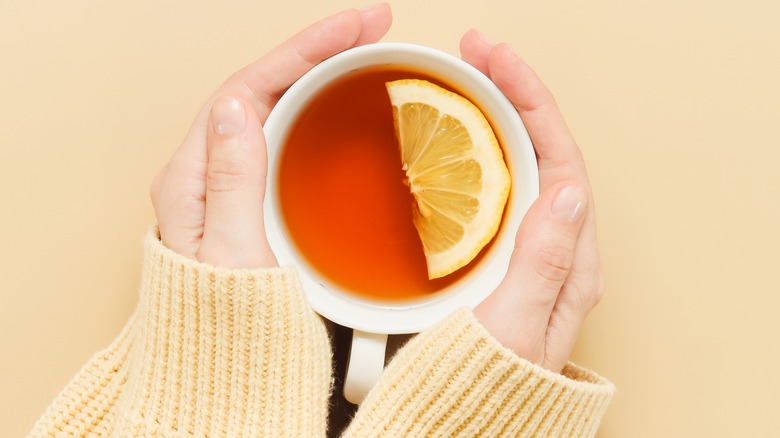 woman holding tea with lemon wedge