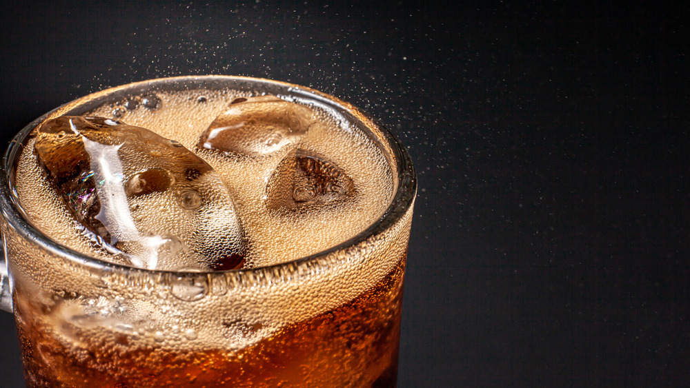 Close up of the top of a glass of bubbly soda with ice.