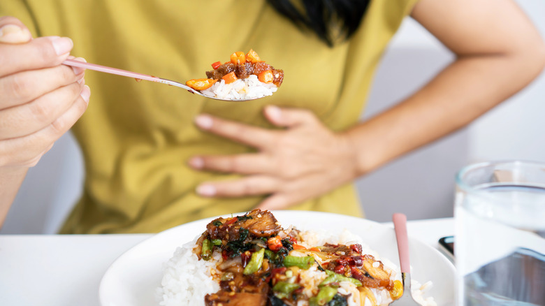 woman with stomachache eating spicy food