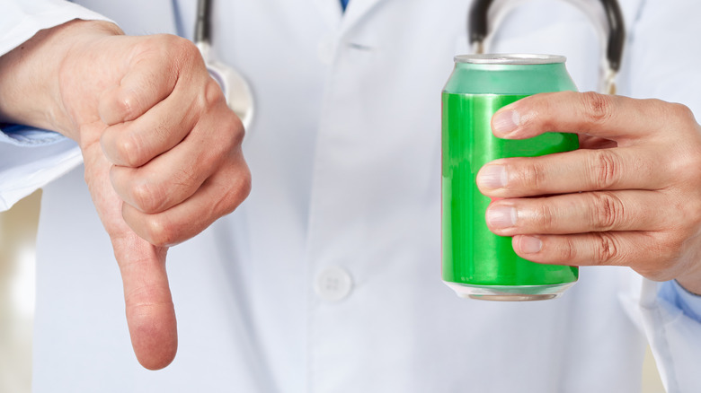 Doctor holding soda can with thumb down