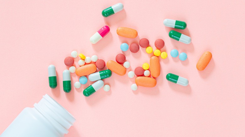 pills and pill bottle on pink background