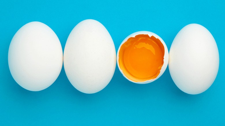 Four eggs (one broken) against a blue background