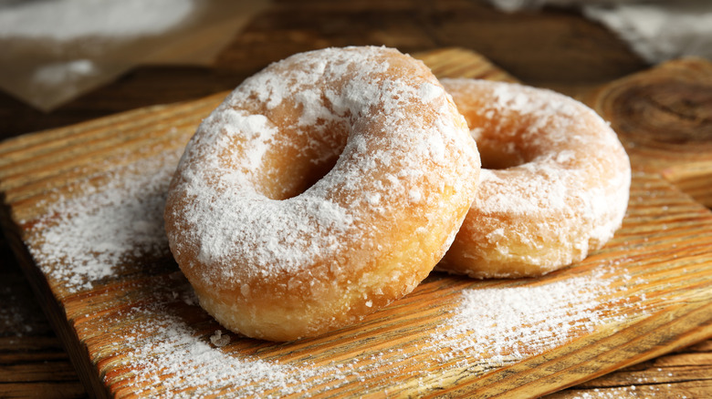 Donuts covered in powdered sugar on wooden board