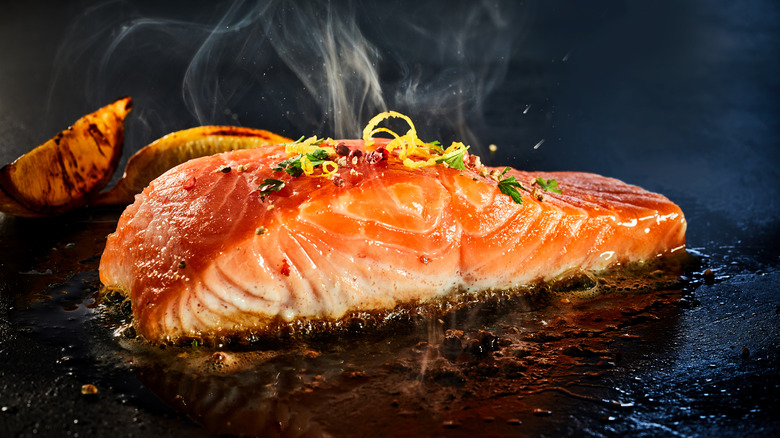 Salmon cooking on a griddle by lemons