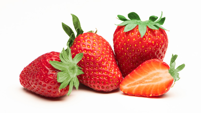 Three strawberries by one halved strawberry