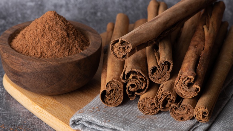 A bowl of powdered cinnamon by cinnamon sticks