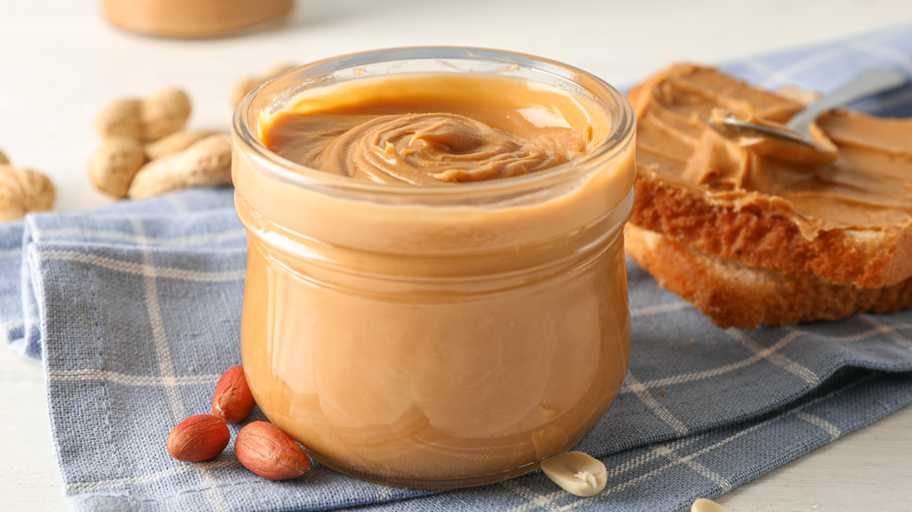 A glass jar of peanut butter on a blue and white napkin