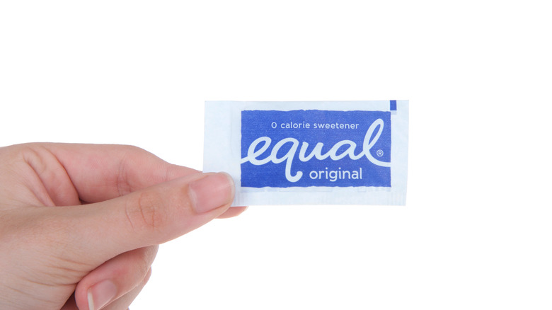 hand holding a packet of equal sweetener