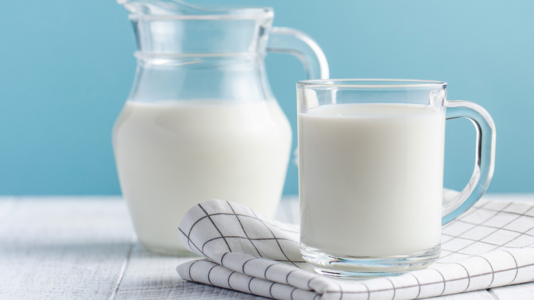 Glass of milk on a napkin with pitcher