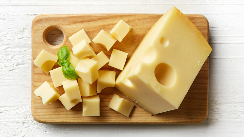 Wedge of Swiss cheese next to cheese cubes