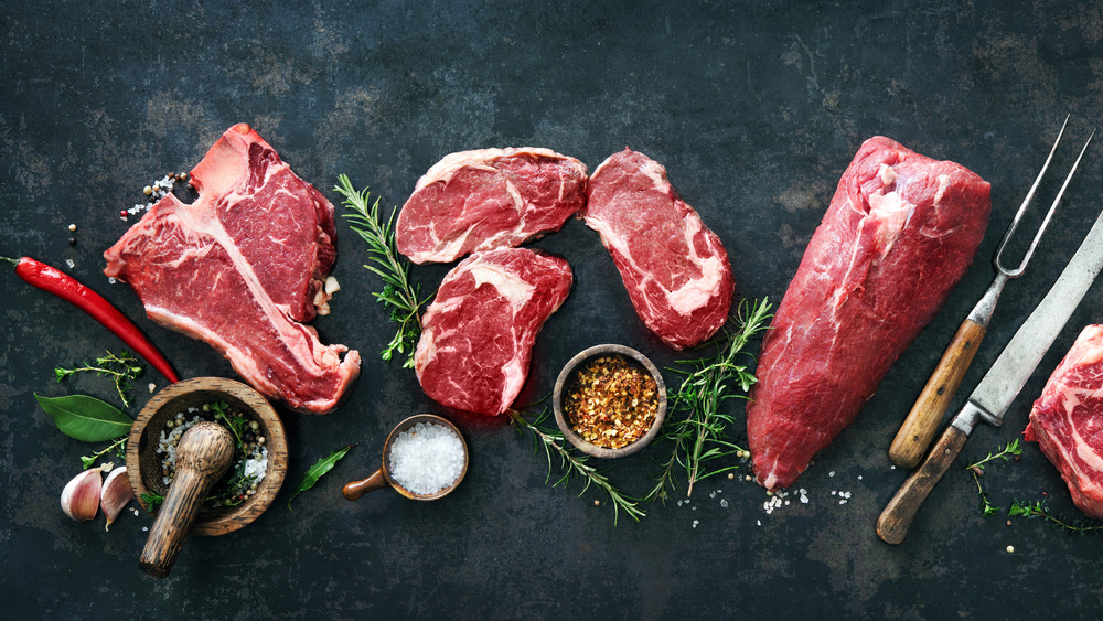 Various cuts of raw steak on a slate board