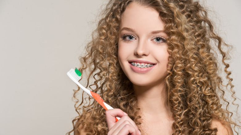 Girl with braces holds a toothbrush