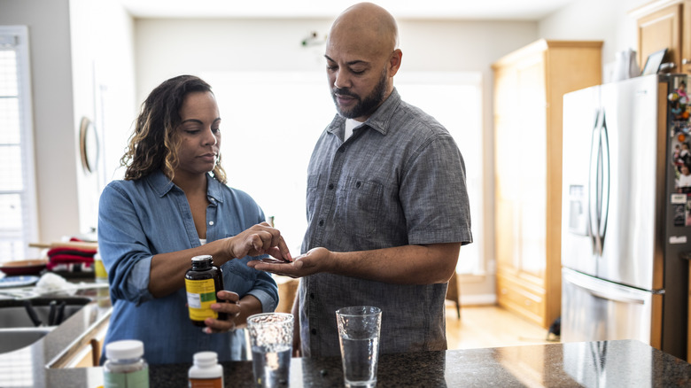 wife handing husband a supplement