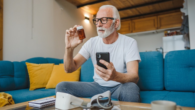 older man looking at a supplement bottle