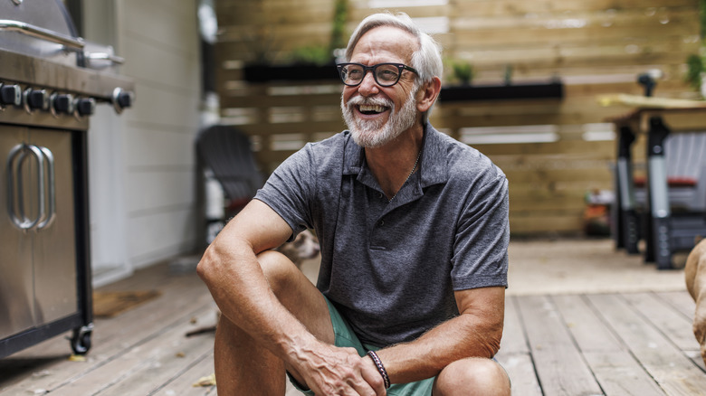 happy older adult male sitting on a wooden floor