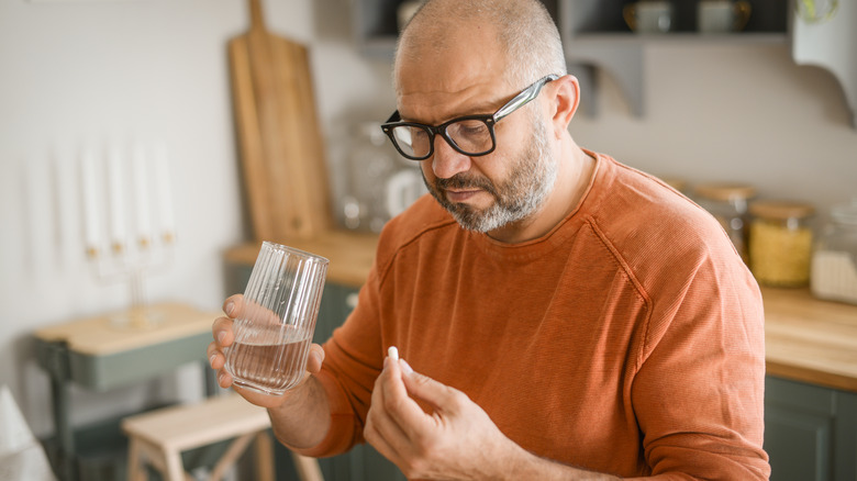 older man looking at his pill