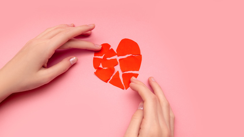 woman putting construction paper heart together