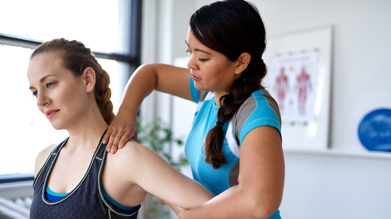 A physical therapist stretching a patient's shoulder