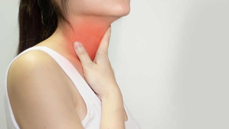 Woman with sore throat and hand near throat