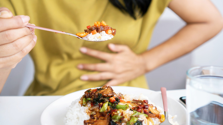 Woman eating spicy food holding her stomach