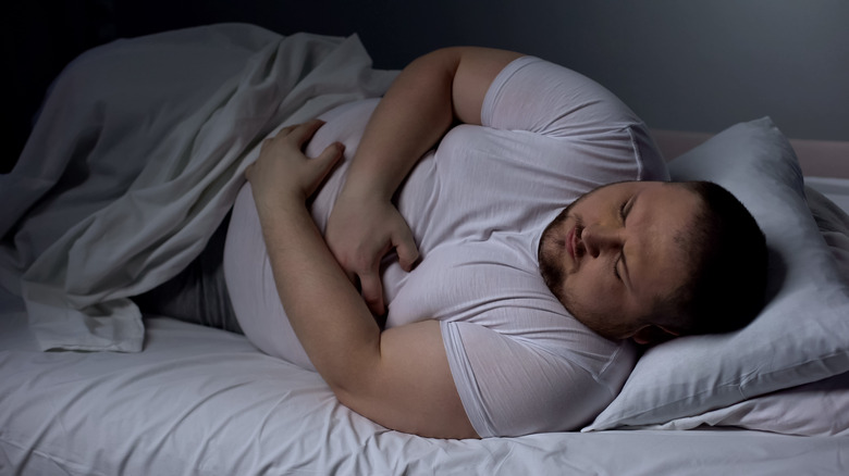 Man suffering from stomach pain in bed