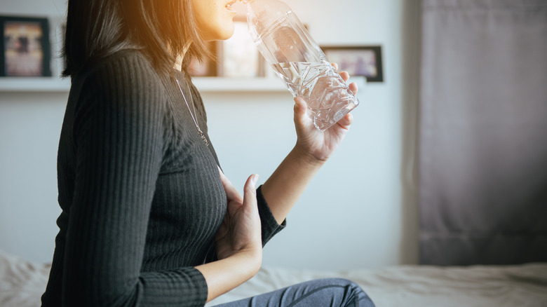 woman with GERD drinking water to take pills