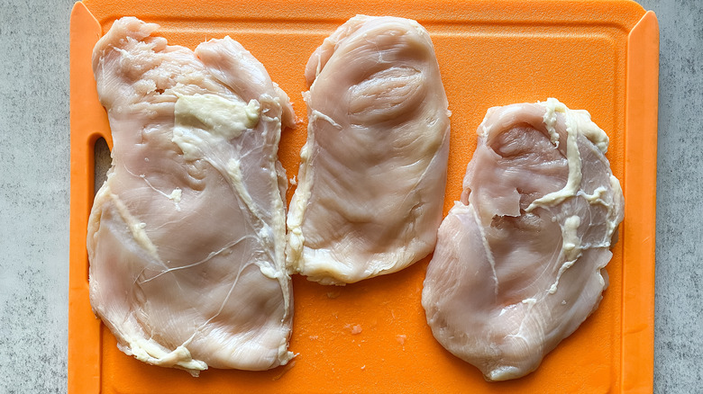 pounded chicken breasts on cutting board