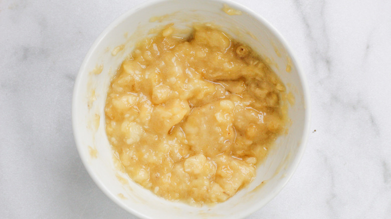 mashed bananas mixed with eggs, butter, maple syrup, and vanilla in a white bowl