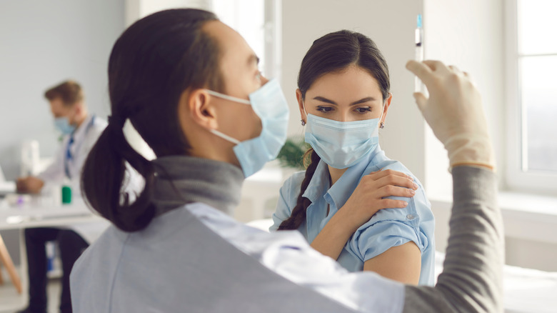 doctor inspecting syringe before injecting patient