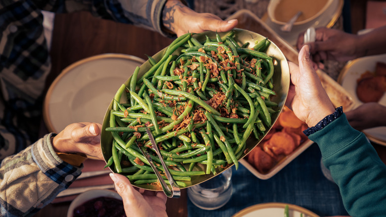 passing platter of green beans at the table