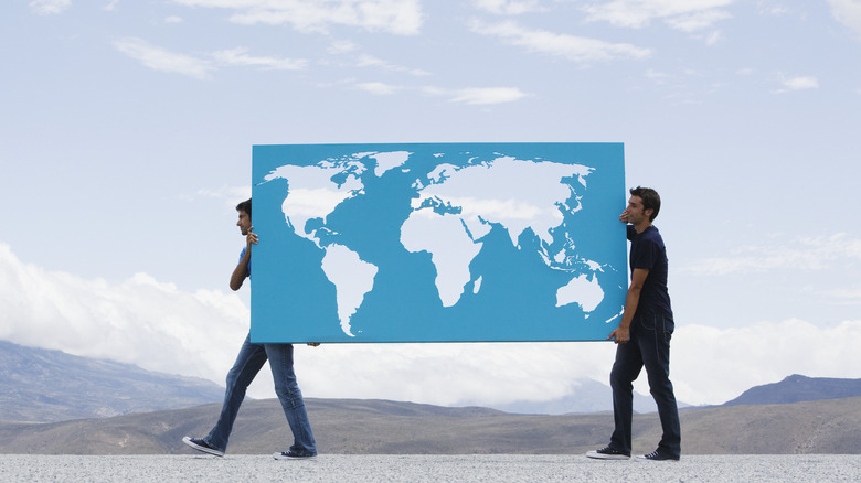 two men carrying map of world