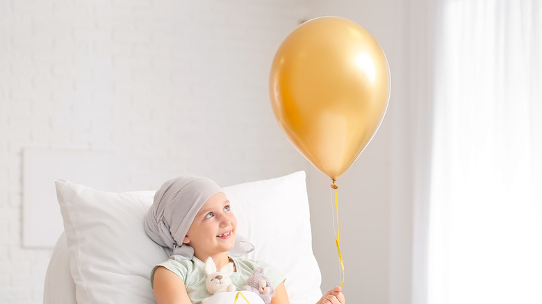 young girl with balloon in hospital bed undergoing chemotherapy