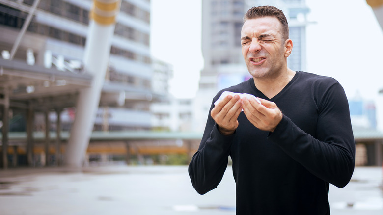 man sneezing without covering face