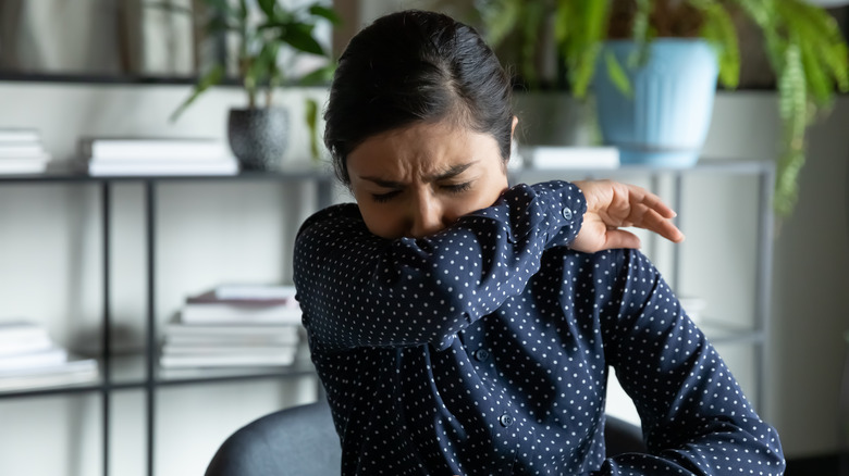 woman sneezing at work