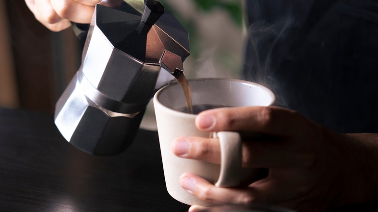 barista pouring coffee into mug