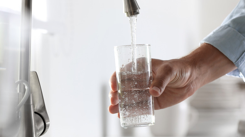 person pouring water into glass