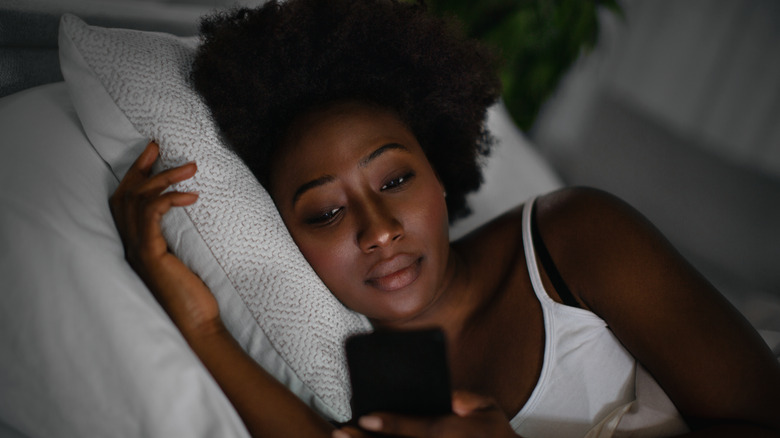 Woman laying in bed texting