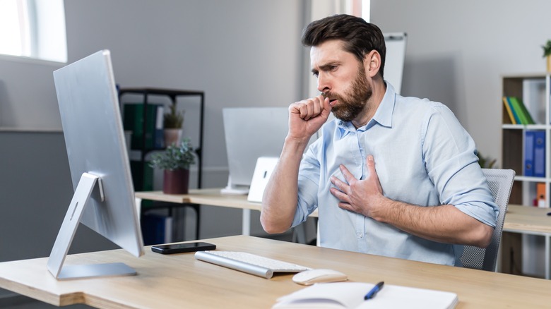 Man in an office coughing