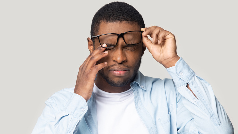 man wearing glasses rubbing eyes