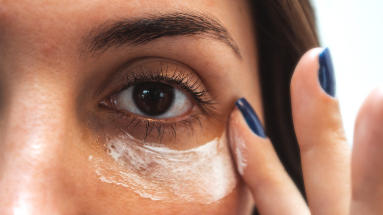 woman applying sunscreen to undereye