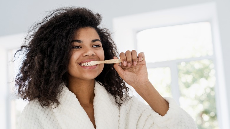 person brushing teeth in bath robe