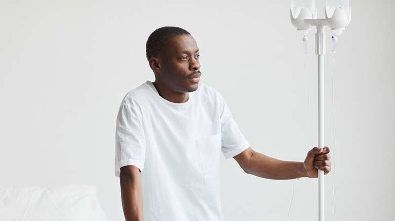 African man standing with IV drip stand