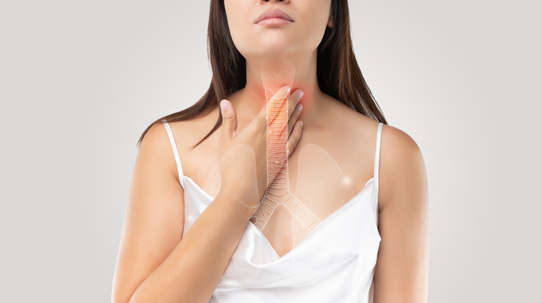 woman holding throat with depiction of esophagus superimposed over her