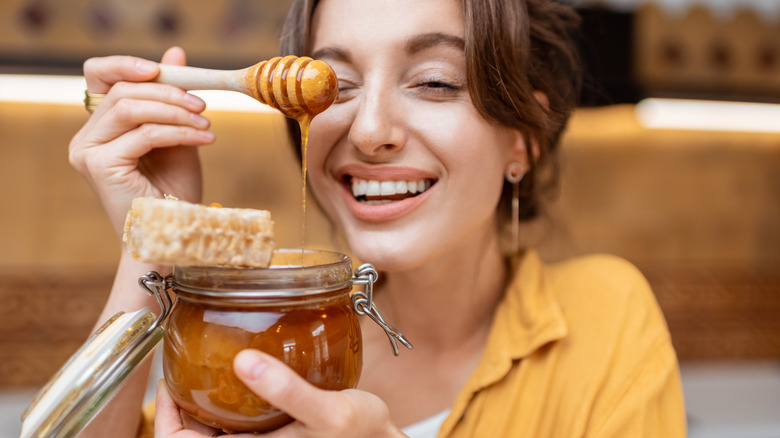 smiling woman holding honey jar 