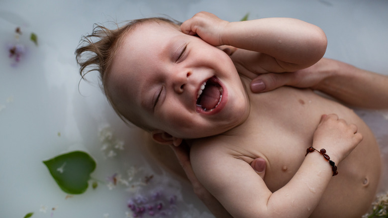 Laughing baby in milk bath
